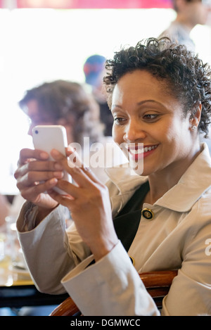 La vita della città. Un gruppo di persone in un café, controllando la loro smart phone. Foto Stock