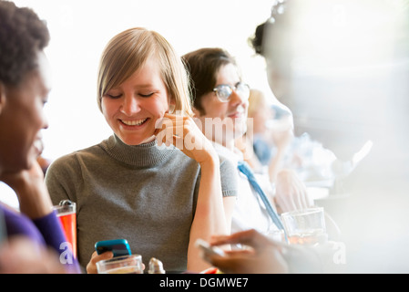 La vita della città. Un gruppo di persone in un café, controllando la loro smart phone. Foto Stock