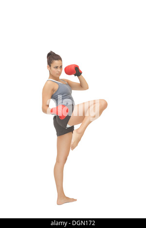 Concentrando sporty brunette kick boxing Foto Stock