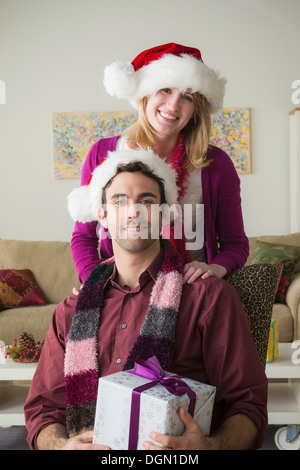 Ritratto di coppia giovane indossando cappelli di Babbo Natale Foto Stock