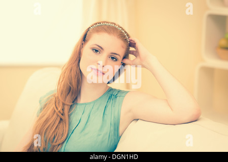 Riflessivo redhead seduta sul divano sorridente in telecamera Foto Stock