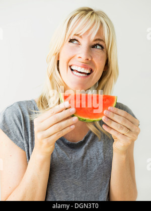 Studio ritratto di donna bionda mangiando anguria Foto Stock