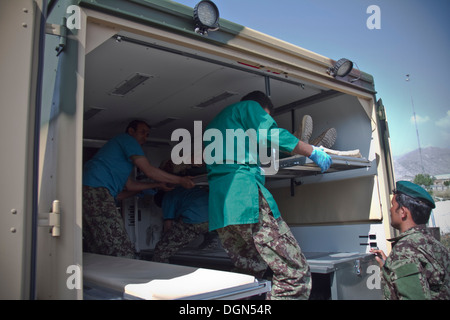 Provincia KHOWST, Afghanistan - I Medici con l esercito nazionale afgano carico vittime simulata nella parte posteriore di un campo per lettiera ambulanza, durante una massa-casualty esercizio su Camp Parsa, Afghanistan, Ottobre 12, 2013. Foto Stock