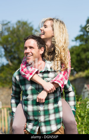 Uomo di dare la sua bella ragazza un piggyback ride Foto Stock