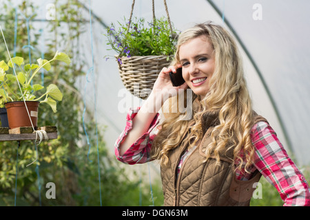 Donna felice telefonare con il cellulare in una casa verde Foto Stock