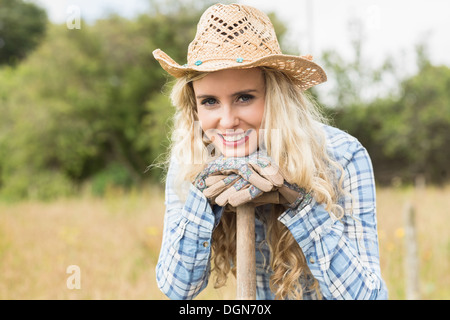 Sorridente donna bionda appoggiata su una pala Foto Stock