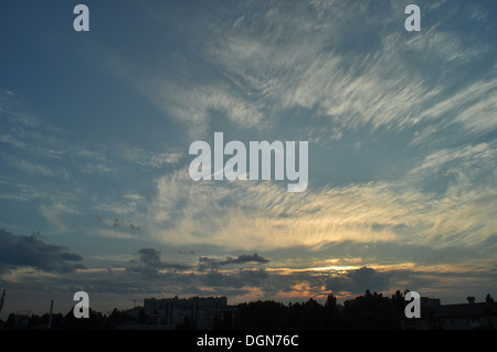 Il sole sotto il blu e il bianco delle nuvole. Foto Stock