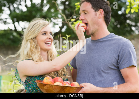 Donna bionda alimentando il suo fidanzato con un Apple Foto Stock