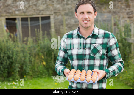 Giovane uomo sorridente holding cartone di uova Foto Stock