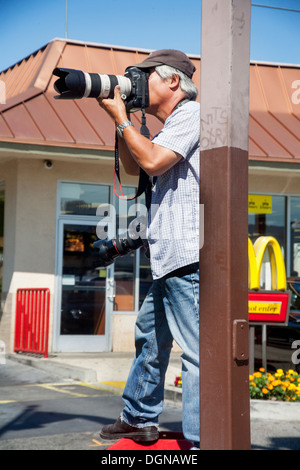 Portante due fotocamere digitali, Associated Press fotografo Nick Ut copre una dimostrazione del lavoro in una Los Angeles parcheggio. Foto Stock