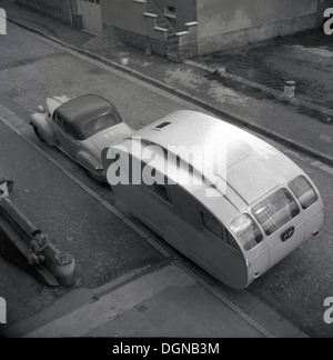 Quadro storico,anni cinquanta di una vettura e una forma curva caravan in una strada laterale in Francia. Un bambino piccolo con beret guardando. Foto Stock