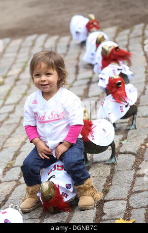 Boston, Massachusetts, USA. 23 Ott, 2013. Anysia Barlow, 2, di Boston sorriso come ella controlla il famoso ''make modo per le ochette'' statua in Boston Public Garden di Boston, Massachusetts che è decorato in Boston Red Sox maglie e le barbe come Boston Red Sox prendere a Saint Louis Cardinals nella serie Mondiale. Credito: Nicolaus Czarnecki/METRO US/ZUMAPRESS.com/Alamy Live News Foto Stock