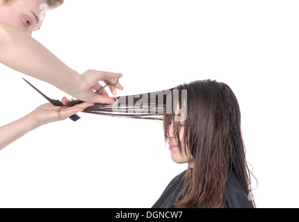 Giovane donna avente un taglio di capelli con un parrucchiere rifilatura il suo fringe sui suoi lunghi capelli bruna, isolato su bianco Foto Stock