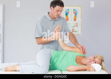 Bello fisioterapista manipolazione del braccio di pazienti Foto Stock