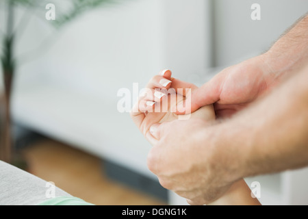 Fisioterapista la massaggiatura della mano di un paziente Foto Stock