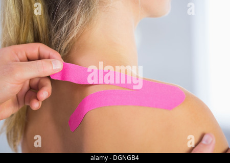 Fisioterapista applicazione kinesio nastro su pazienti di sesso femminile spalla Foto Stock