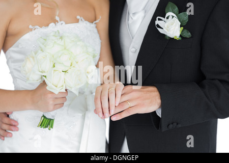 I giovani sposi in posa tenendo le mani Foto Stock