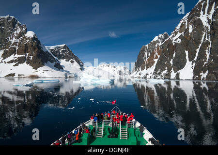 I visitatori sulla prua della Expedition nave da crociera, MS Expedition, osservando il paesaggio si riflette nel canale di Lemaire Foto Stock