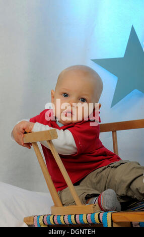 Piccolo Ragazzo seduto su una slitta, stella sul retro Foto Stock