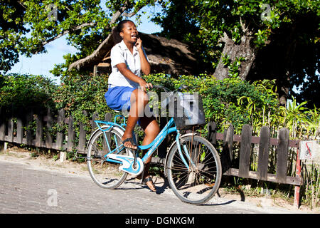 Donna che parla su un telefono cellulare mentre in sella ad una bicicletta, La Digue Island, Seychelles, Africa, Oceano Indiano Foto Stock