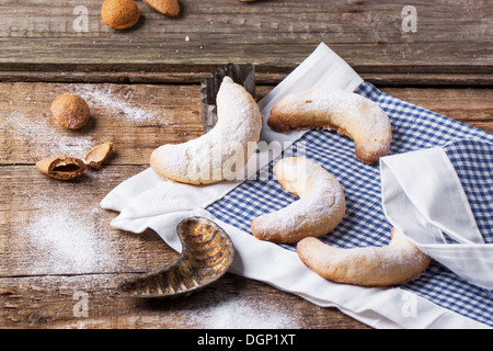 Lo zucchero in casa cookie crescent servita con accessori vintage, mandorle e tessuto sopra il vecchio tavolo in legno Foto Stock