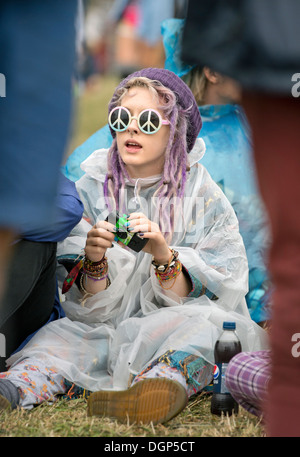 Il Festival della lettura - una ragazza in un poncho di plastica con CND occhiali da sole Aug 2013 Foto Stock