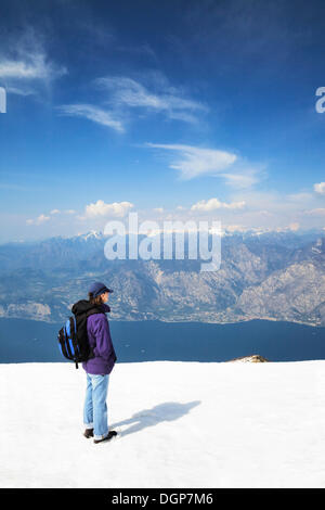 Escursionista godendo la vista dal Monte Baldo sul Lago di Garda e le Alpi, il Lago di Garda, Lombardia, Italia, Europa Foto Stock