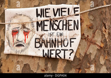 Poster di protesta "Wie viele Menschen ist ein Bahnhof wert?', tedesco per "una stazione ferroviaria vale la pena di quante persone?" su un vecchio albero Foto Stock