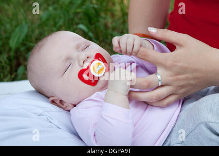 A pochi mesi di età bambino aggrappato alle dita di sua madre Foto Stock