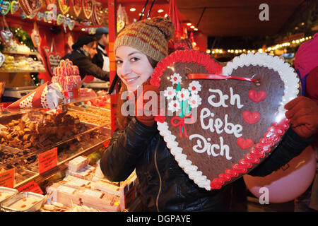 Giovane donna in possesso di un cuore di panpepato con iscrizione "Ich liebe dich", tedesco per "ti amo" presso il mercato di Natale Foto Stock