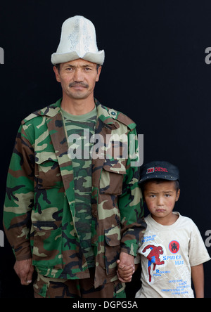 Padre Con Kalpak Hat e con suo figlio indossando un cappello, Kochkor mercato animale, Kirghizistan Foto Stock