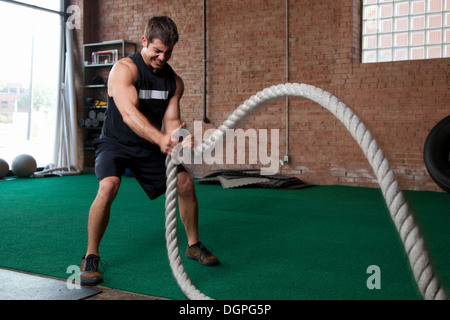 Culturista maschio utilizzando corde in palestra Foto Stock