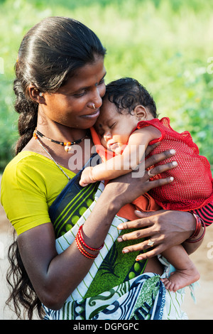 Felice di casta inferiore donna indiana cullano il suo bambino. Andhra Pradesh, India Foto Stock