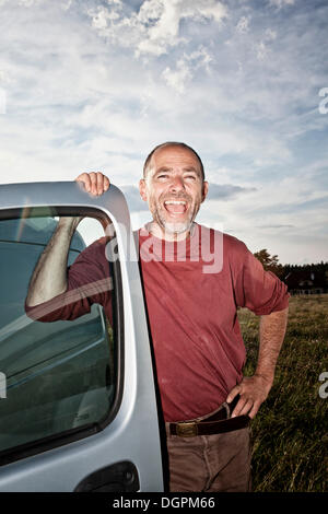 Uomo di ridere appoggiato su di una porta per auto Foto Stock