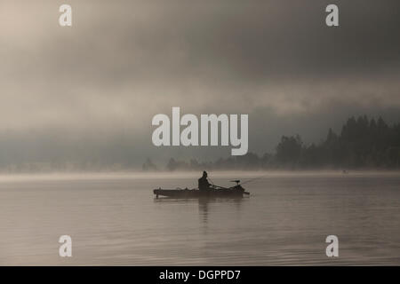 Pescatore di mattina presto con la nebbia nella luce del mattino sul lago Weissensee, Carinzia, Austria, Europa Foto Stock