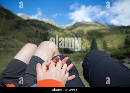 Coppia sposata tenendo reciprocamente le mani mentre si affaccia su un panorama di montagna, valle Debanttal, Tirolo, Austria, Europa Foto Stock