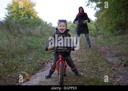 Little Boy è in sella alla sua bicicletta giù per un sentiero di bosco, ridendo, Brandenburg Foto Stock