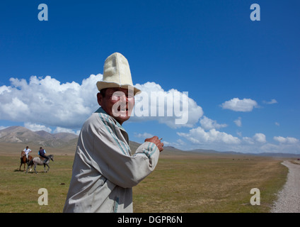 Il vecchio uomo Con Kalpak Hat godendo il cavallo di gioco, Song Kol Area, Kirghizistan Foto Stock