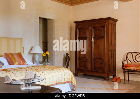 Legno di antiquariato francese armadio in camera da letto con Trisha Tucker letto di seta copre e un Diedre Dyson rug. Foto Stock