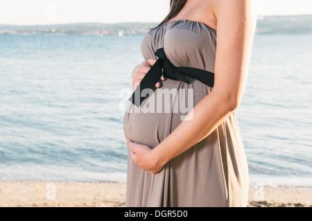 Donna incinta sulla spiaggia Foto Stock