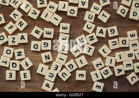 Lettere di plastica da un gioco di ortografia dei bambini, jumbled su un tavolo di legno Foto Stock