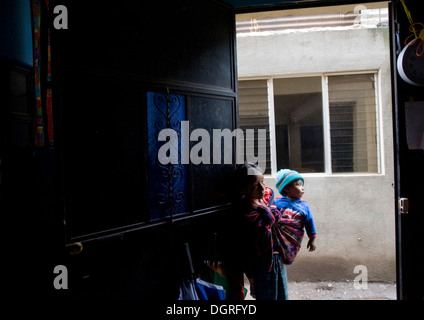 Guatemala ragazza porta il suo bimbo piccolo fratello guarda nella classe di età prescolare a San Jorge La Laguna in Solola, Guatemala. Foto Stock