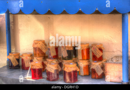 Colorati vasi di marmellata fatta in casa con etichette scritte a mano in cornice blu Foto Stock