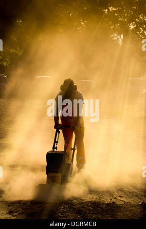 Lavoratore di strada operando una piastra di vibratore compatto per una strada polverosa, Hesse, PublicGround Foto Stock