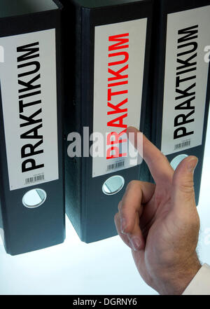 Mano che puntano a una cartella di file denominata "Praktikum', tedesco per "stage" Foto Stock