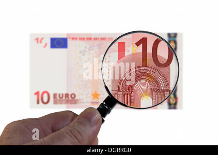 10 di banconote in euro al di sotto di una lente di ingrandimento immagine simbolica, osservazione dell'euro Foto Stock