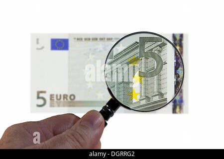 5 di banconote in euro al di sotto di una lente di ingrandimento immagine simbolica, osservazione dell'euro Foto Stock