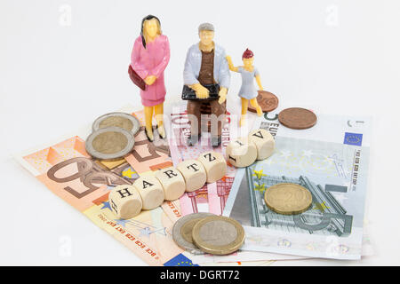 Le figure in miniatura di un gruppo di lavoro di classe famiglia, le banconote in euro, lettera cubi formanti la parola 'Hartz IV", Tedesco il sostegno al reddito Foto Stock