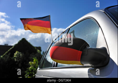 Bandiera della Germania e bandiera tedesca su uno specchio esterno su una vettura contro il cielo blu, Ringsheim, Baden-Wuerttemberg Foto Stock