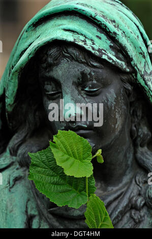 Scultura femmina su una tomba, il suo mento è coperto da una foglia di tiglio, Cimitero di St. John, Norimberga, Media Franconia, Bavaria Foto Stock